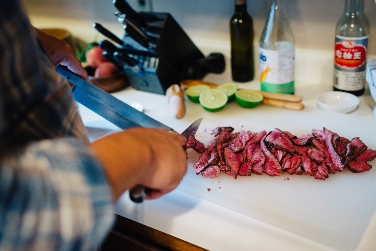 in kitchen cutting up piece of red steak