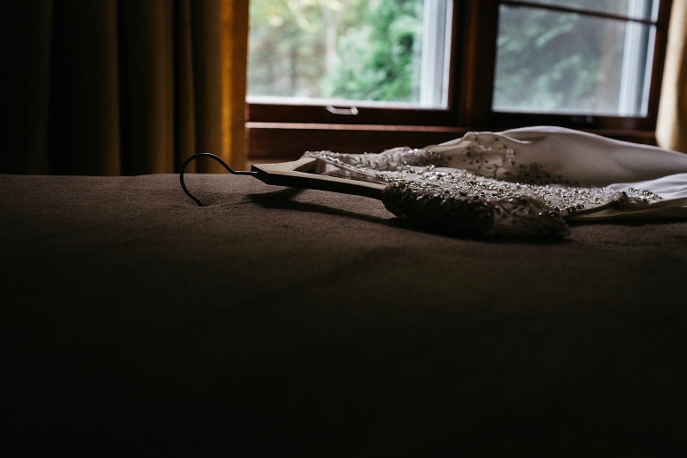 Wedding dress on hanger laying on bed