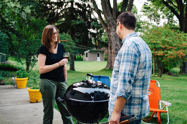 Man grilling outside with woman sipping glass of wine