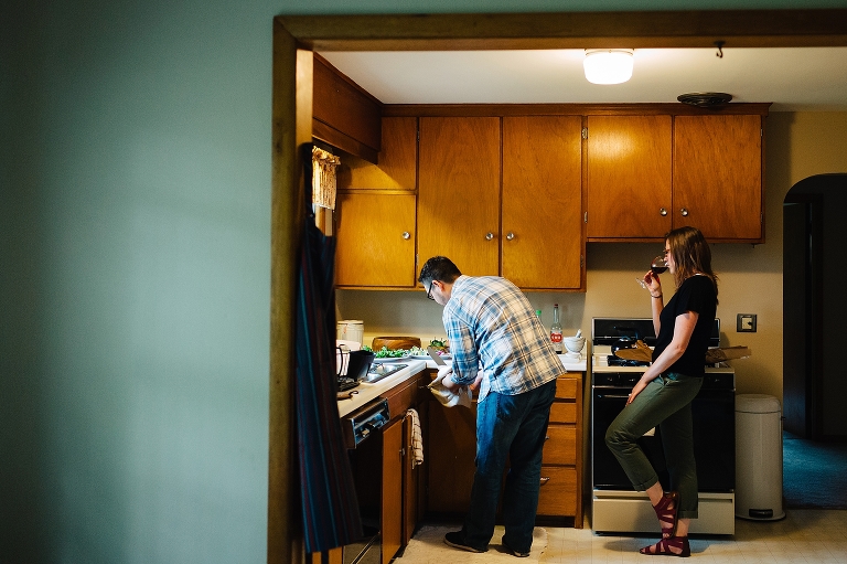 kitchen with man cooking and woman sipping glass of wine