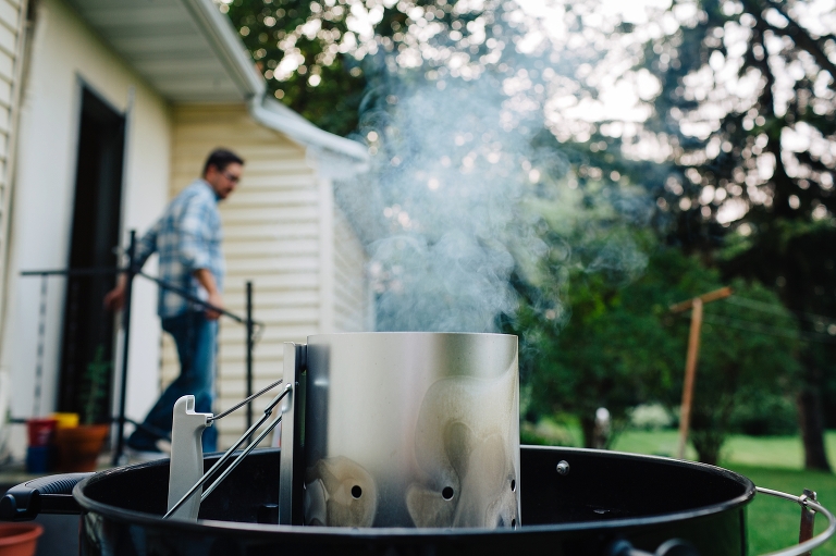 Man walking outside of yellow house to smoking grill