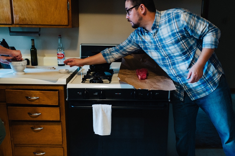 Man in kitchen seasoning piece of red meat