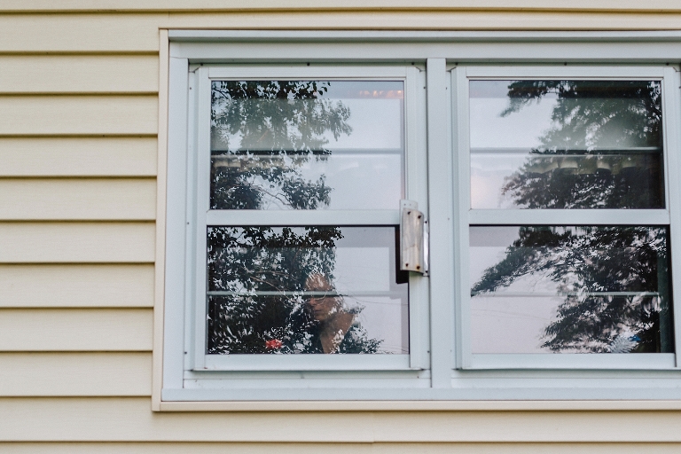 Yellow house with white windows, see through windows woman standing inside the house.