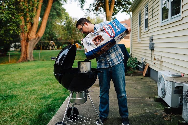 Man pours charcoal into grill in backyard