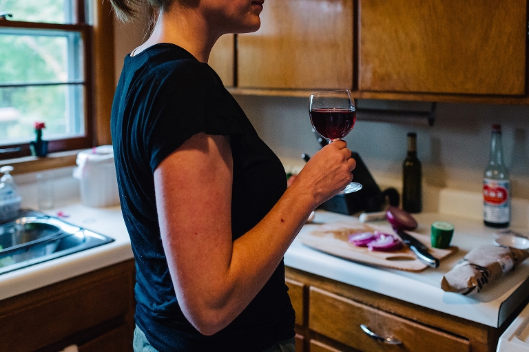 Woman cooking in kitchen drinks glass of wine