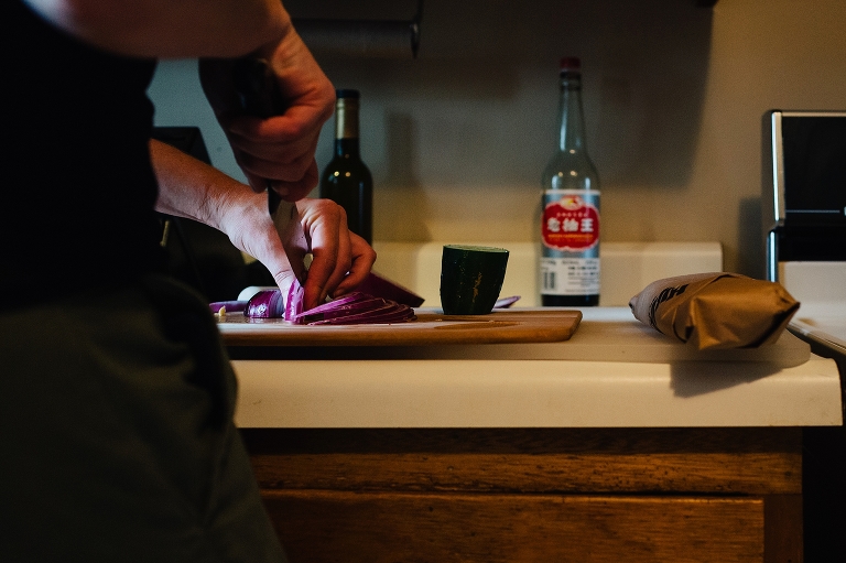 Woman in kitchen cutting up red onion on cutting board