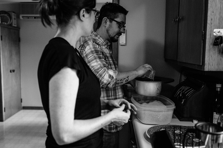 Black and white. A couple in kitchen cooks a pot of rice.