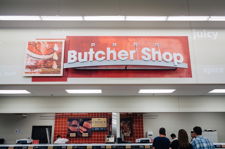 A couple stands in line at the butcher shop in grocery store