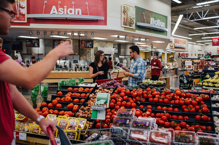 Man and woman in grocery store pick out red onions and add them to shopping basket