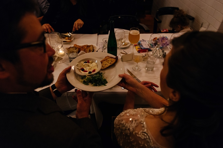 Bride and groom pass appetizers at dinner