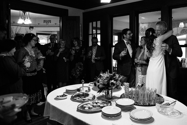 Black and white. Family drinks champagne and bride hugs father after the wedding