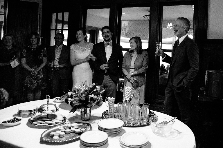 Black and white. Bride and groom stand with family at wedding after party