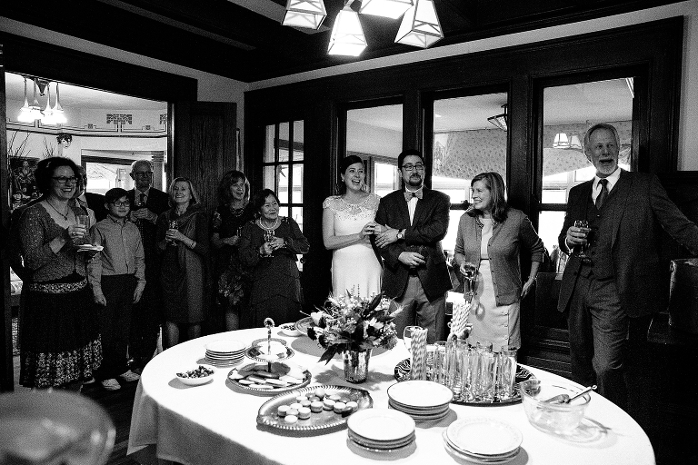 Black and white. Bride and groom stand with family at wedding after party