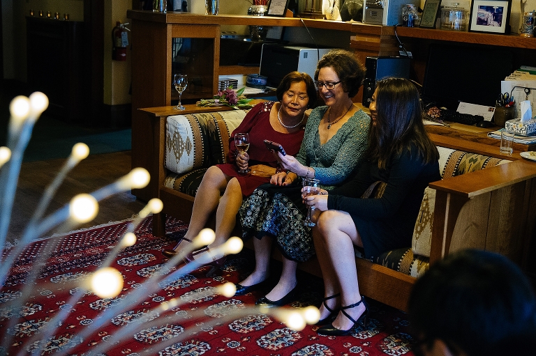 Family look at photos on phone at wedding party