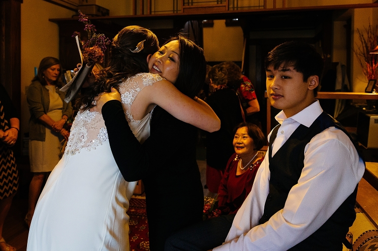 Family hugs the bride after wedding