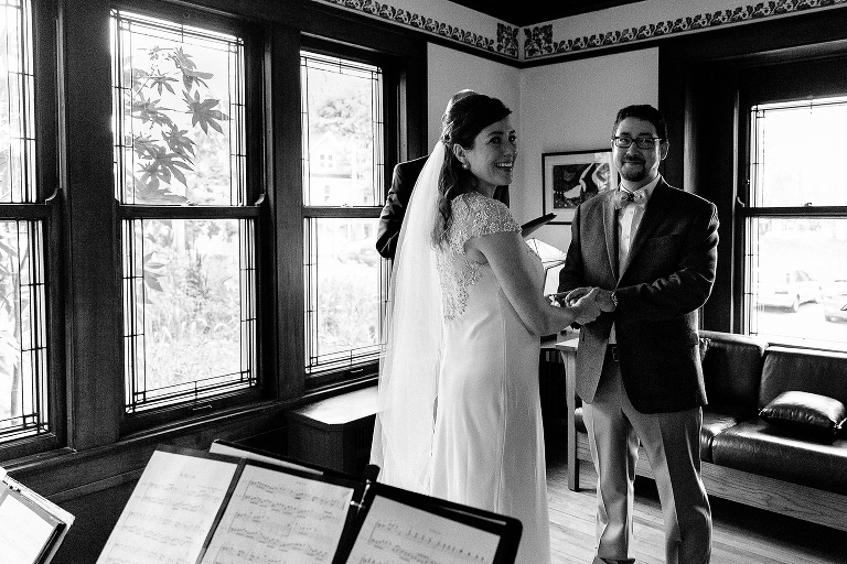 Black and white. Bride and groom hold hands during wedding ceremony.