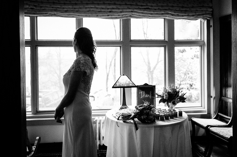 Black and white. Bride looks out the window before wedding