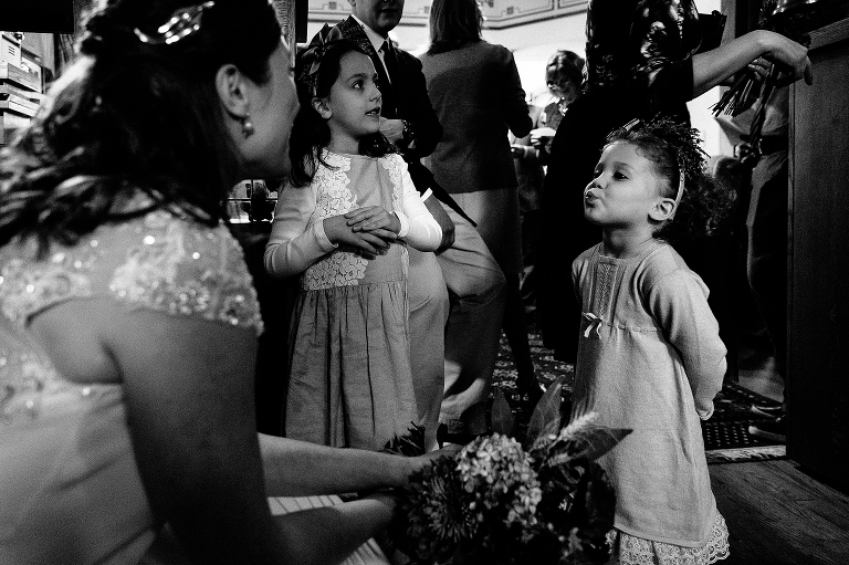Black and white. Bride talks to the two flower girls before wedding
