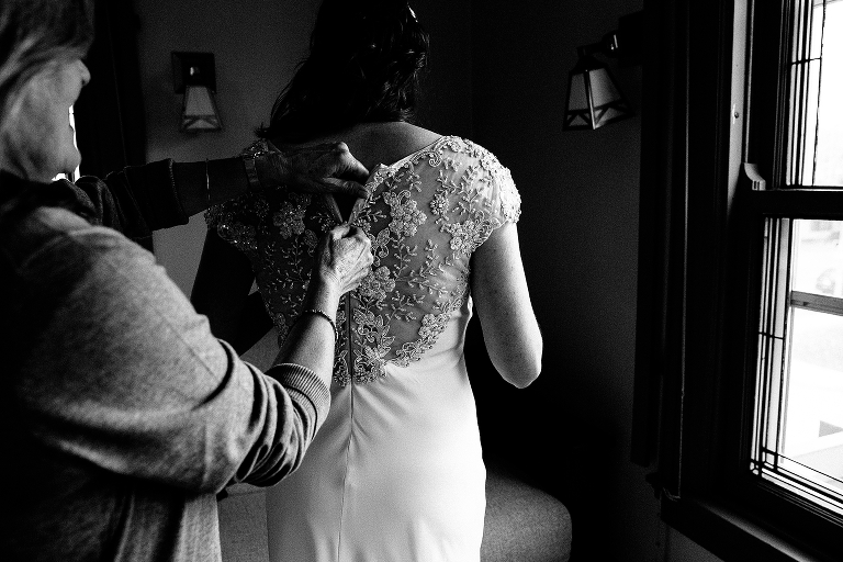 Black and white. Bride gets help zipping up wedding dress