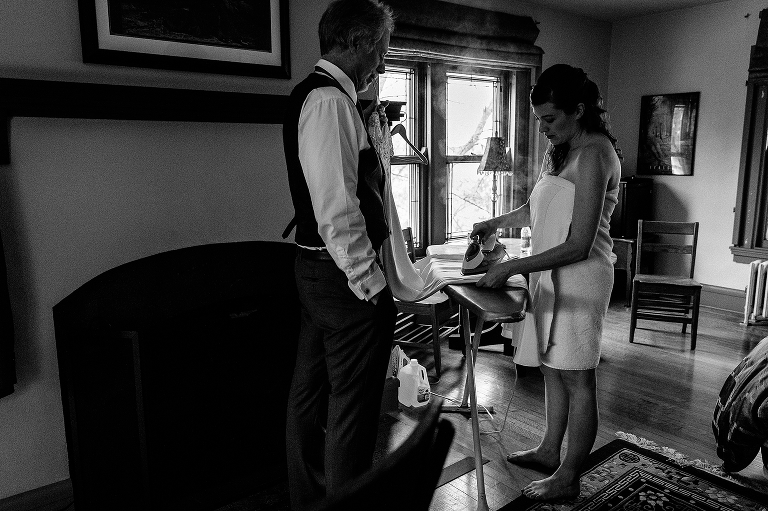 Black and white, bride wearing a towel irons her wedding dress