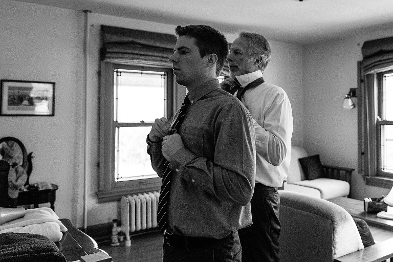 black and white, two men put on ties for wedding