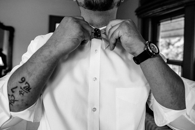 black and white. Groom puts on bow tie