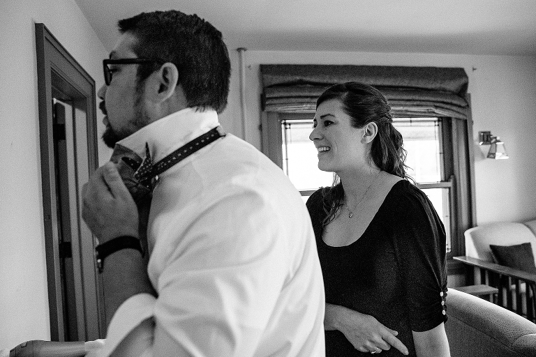 Woman watches groom put on bow tie