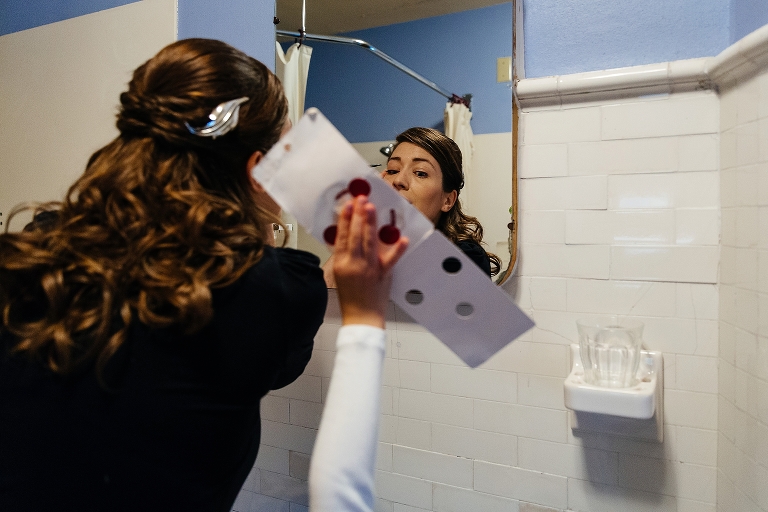 Bride putting on makeup in mirror