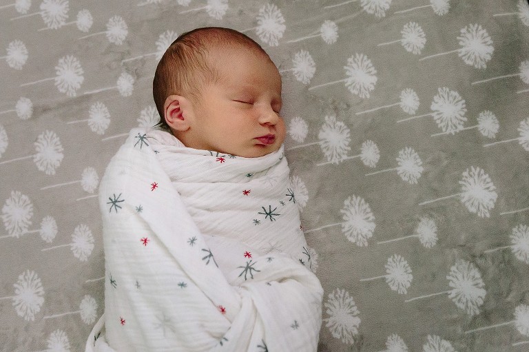 Sleeping swaddled newborn on crib sheet 