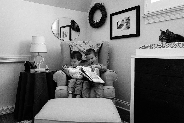 Two brothers hold newborn sister and prepare to read a story 
