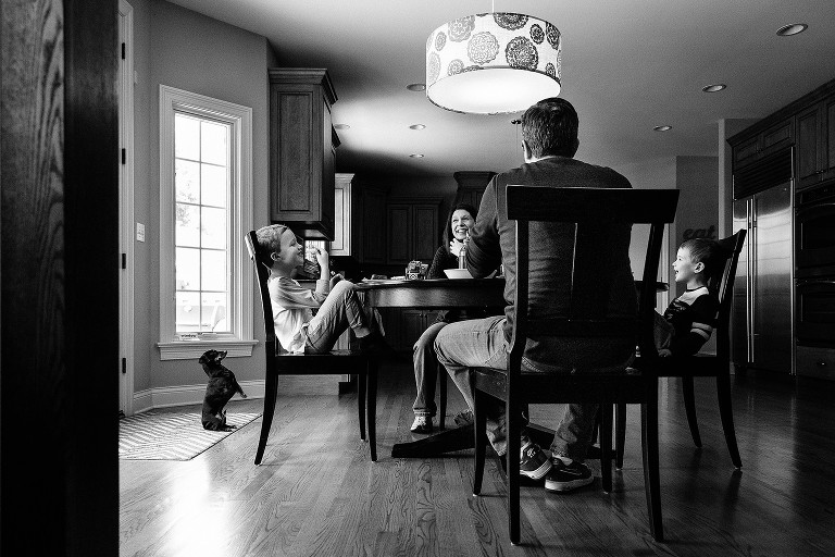 Mom, Dad, dog, and two boys laughing in the kitchen