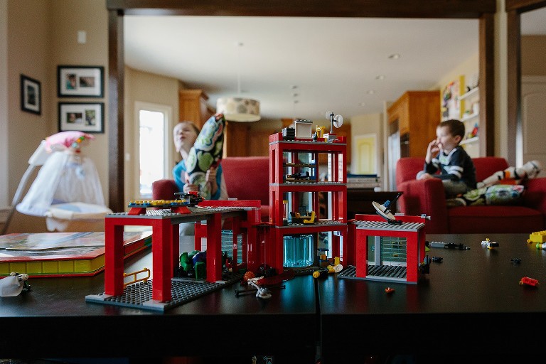 Focus on red large Lego set while two boys play and talk in the background 