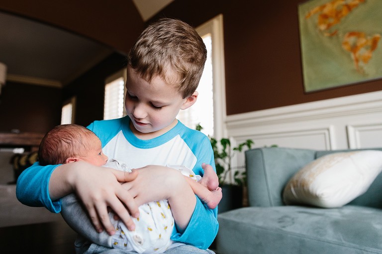 Baby brother holds newborn sister 