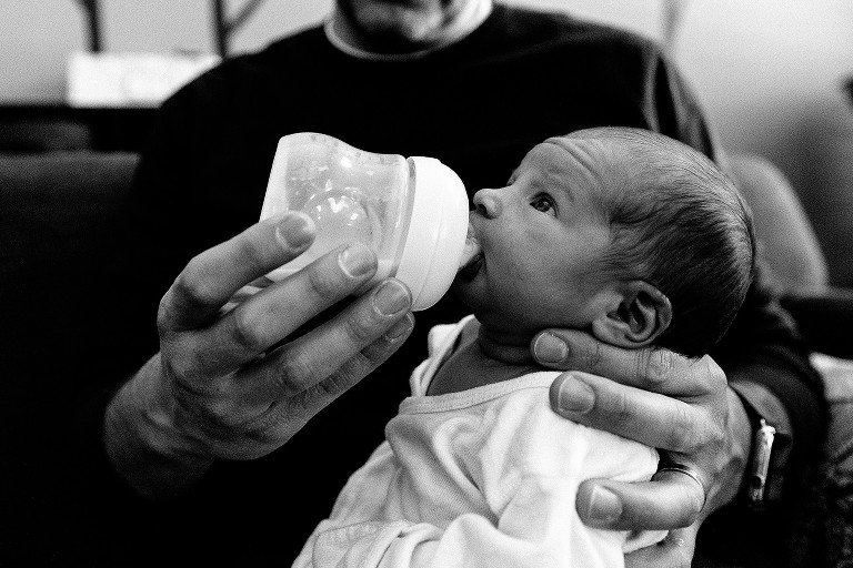 dad gives bottle to newborn girl 