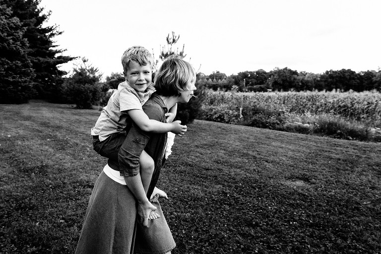 Boy gets piggy back ride from mom at the farm fields 