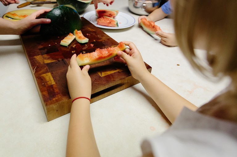Girl holds eaten watermelon in hand, only the rind and small bits of watermelon remain. 