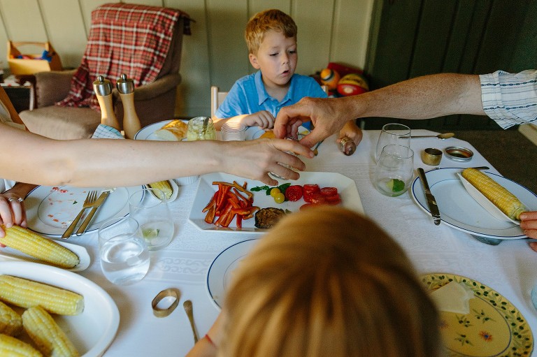 Mom and Dad pass food across the table 