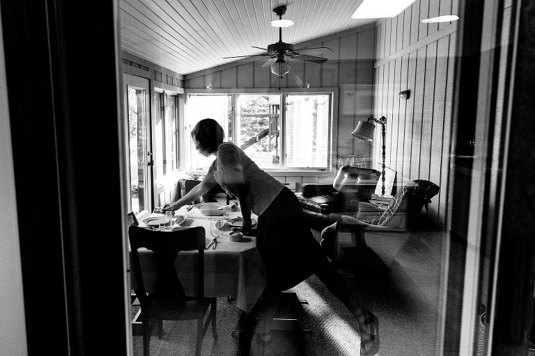 Mom stretches across table set for dinner. 