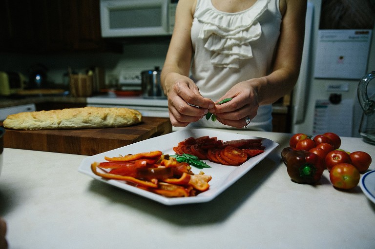 Mom de-stems basil and puts on platter with peppers and tomatoes. 