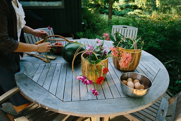 Picnic table full of garden flowers, peppers, tomatoes, and fresh eggs. 