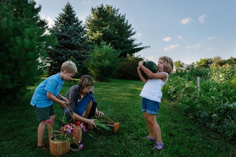 Girl hoists heavy watermelon, mom gathers corn, boy grabs baskets of flowers in the field. 