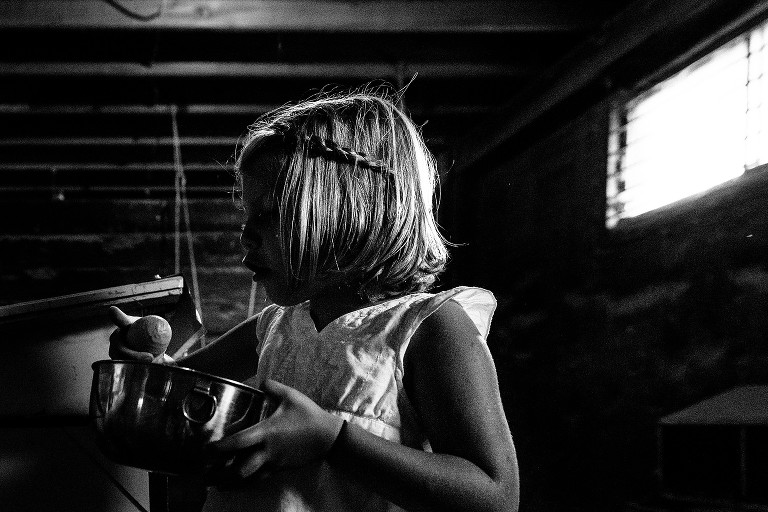 Girl inspects an egg that has several ridge. In the barn.