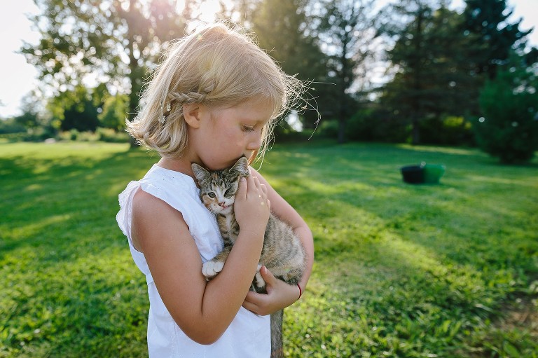 Girl snuggles newborn kitten in afternoon light 