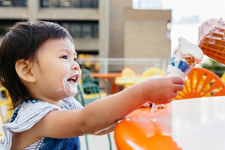girl makes an ice cream cheers with her parent 