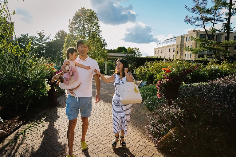 Mom offered daughter a snack while walking. Dad is holding daughter. 