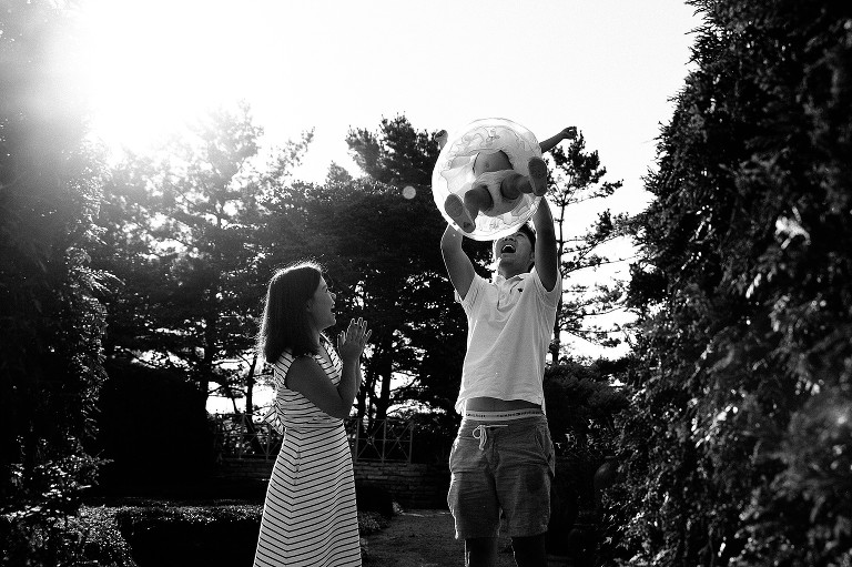 Dad swings daughter in the air, mom claps, sun flare 