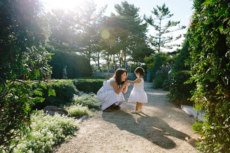 Mom crouches down to talk to daughter face to face in a garden