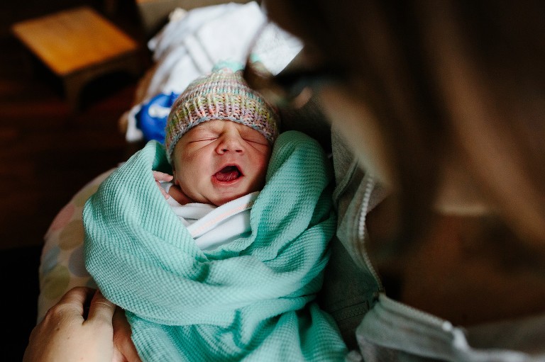 Newborn comes out of a yawn and starts to cry