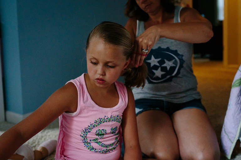 Mom puts daughter's hair in a pony tail. 