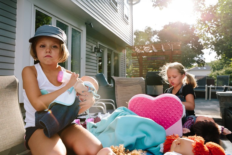 5 year old has serious face while pretend feeding her doll a pretend bottle